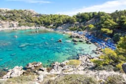 Wide view over the crystal-clear water of Anthony Quinn Bay